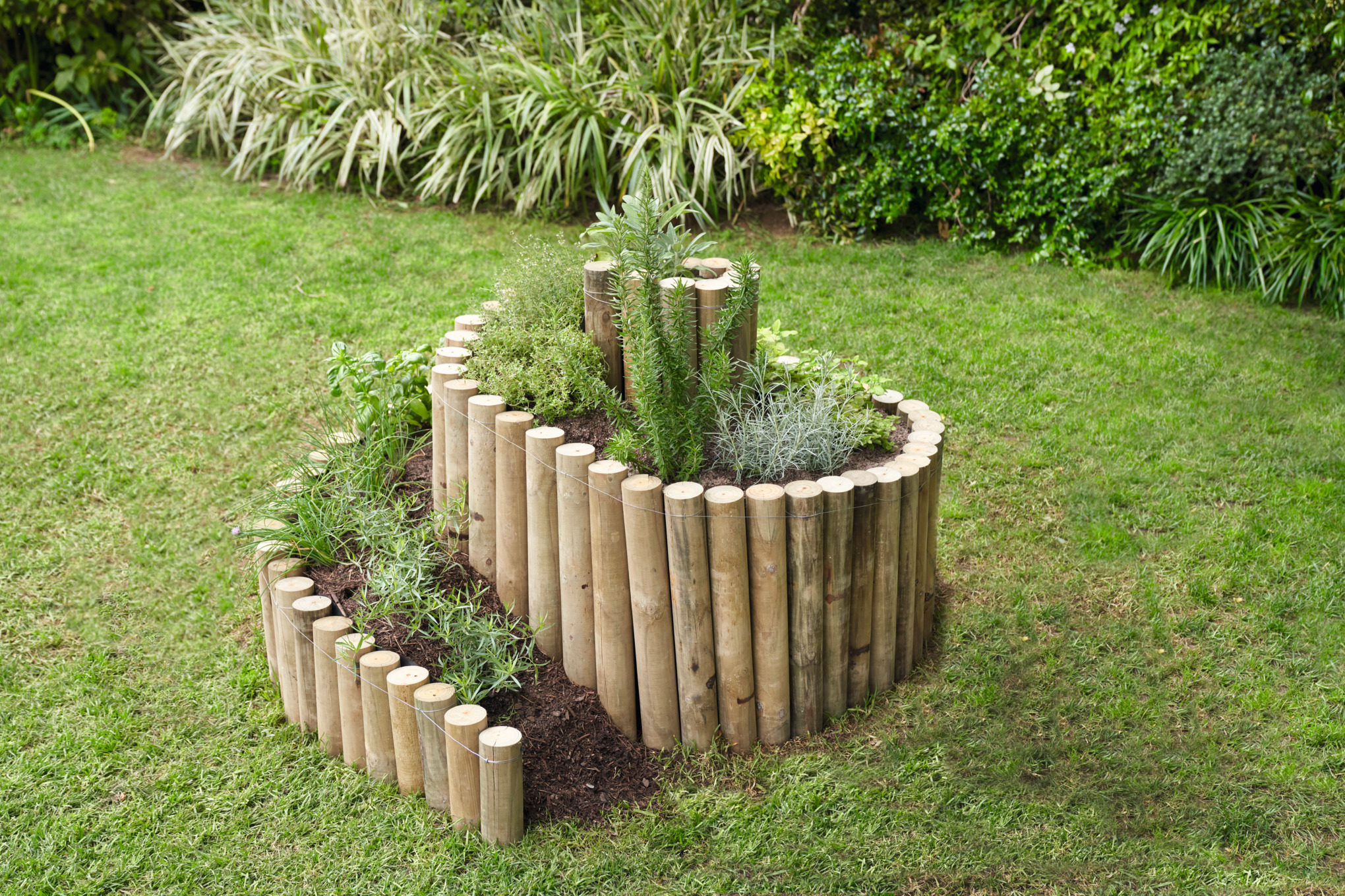 Kräuterspirale mit Holzpflöcken auf einem Gartengrundstück