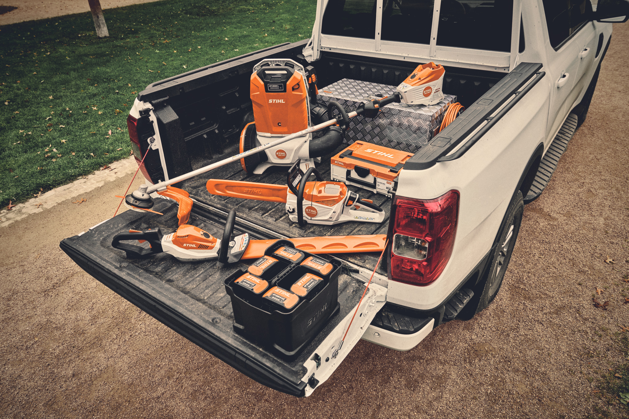 Verschiedene Akku-Geräte des STIHL AP-Systems und die passenden Akkus auf der Ladefläche eines Fahrzeugs