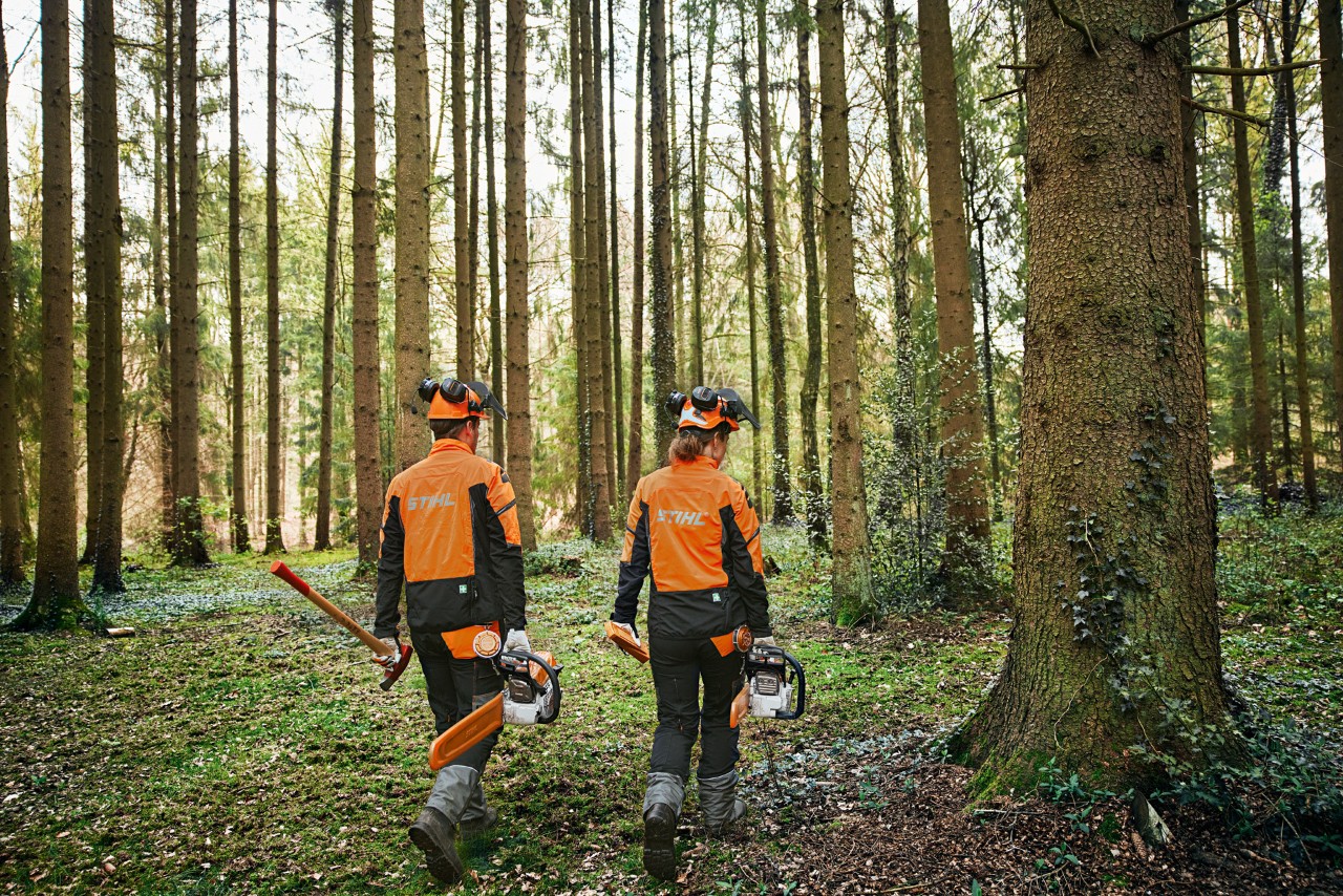 Mann mit STIHL Gehörschutz im Garten vor gestapelten Holzscheiten