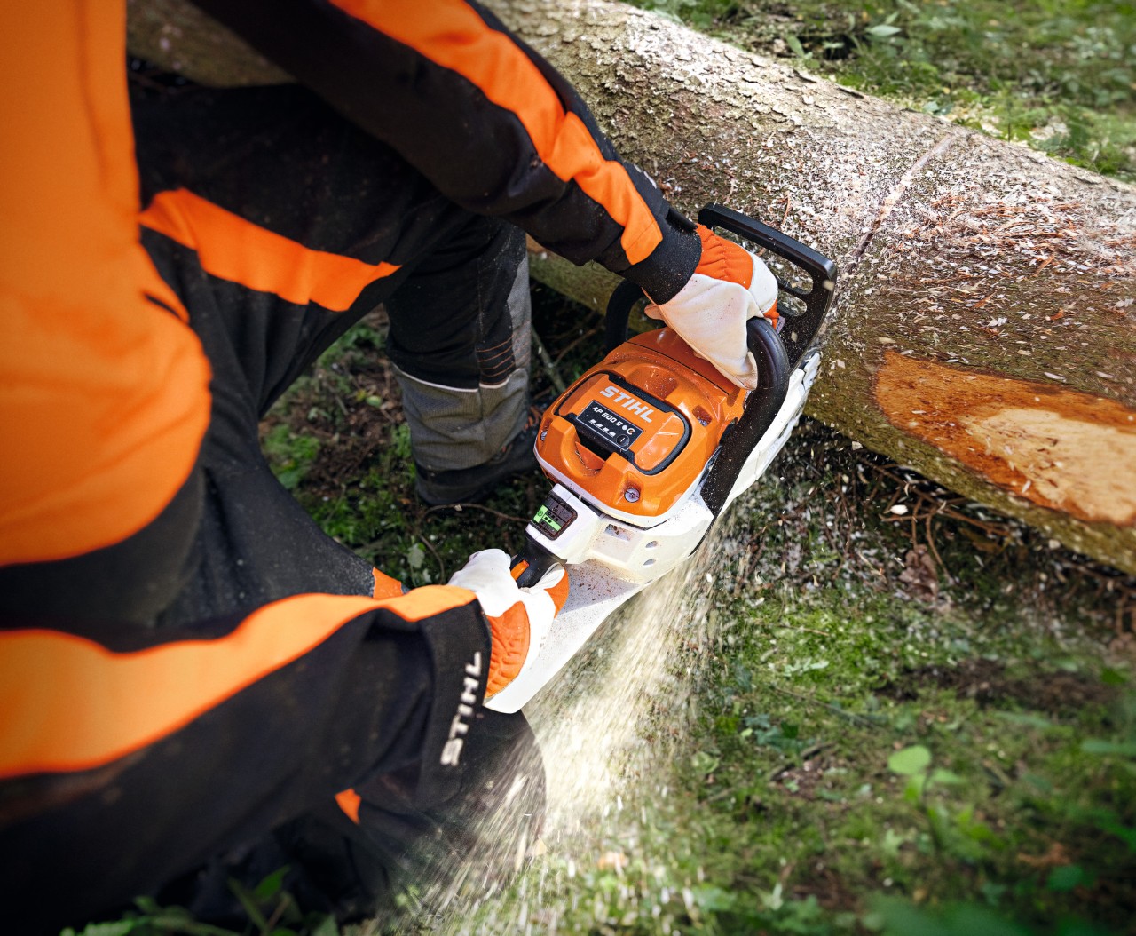 Nahaufnahme, wie jemand mit der Akku-Motorsäge STIHL MSA 300 einen Baumstamm durchtrennt