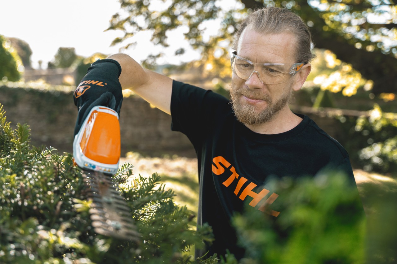 Chefgärtner Andrew Wain schneidet mit einer STIHL Akku-Heckenschere eine Hecke