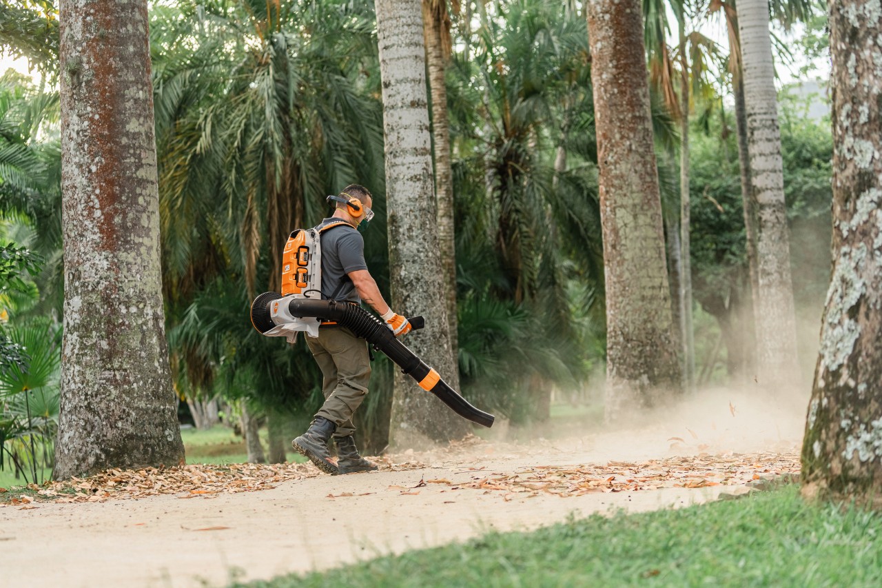 Luiz Carlos, Mitarbeiter im Botanischen Garten, bläst mit einem Laubbläser die Blätter auf dem Weg zusammen