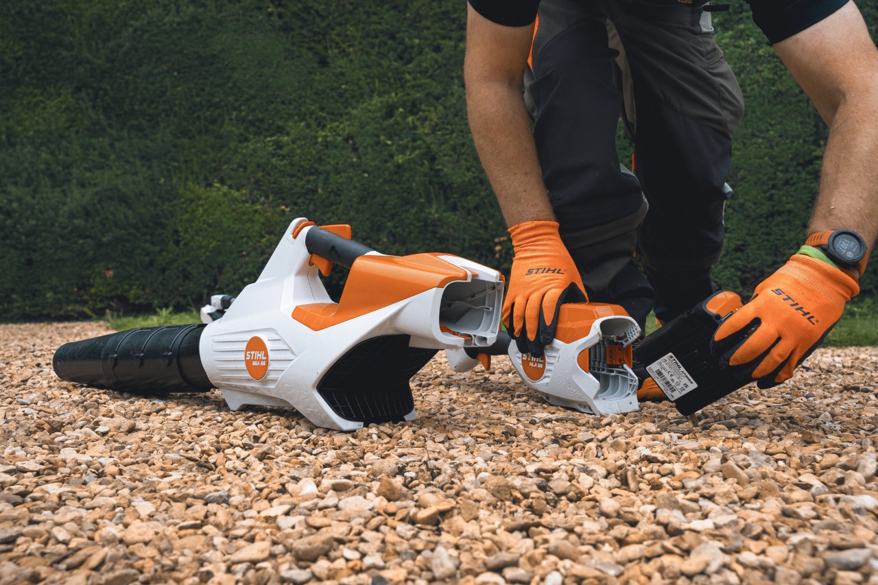 Ein Profi wechselt vor der Hecke des Bathurst Estate den Akku seines STIHL Akku-Laubbläsers