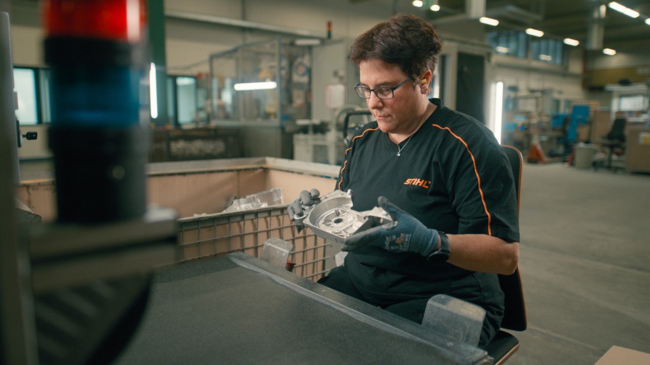 Eine Frau prüft ein Bauteil sorgfältig auf Mängel und Auffälligkeiten