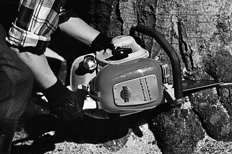 Alte Schwarzweiß-Nahaufnahme, wie jemand einen Baum mithilfe der Motorsäge STIHL Contra fällt