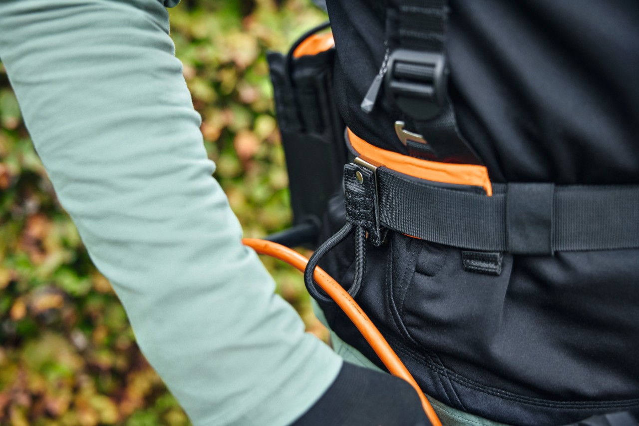 Jemand trägt das modulare Gurtsystem STIHL ADVANCE X-Flex mit einer Akku-Tasche mit Anschlussleitung und Kabelführung