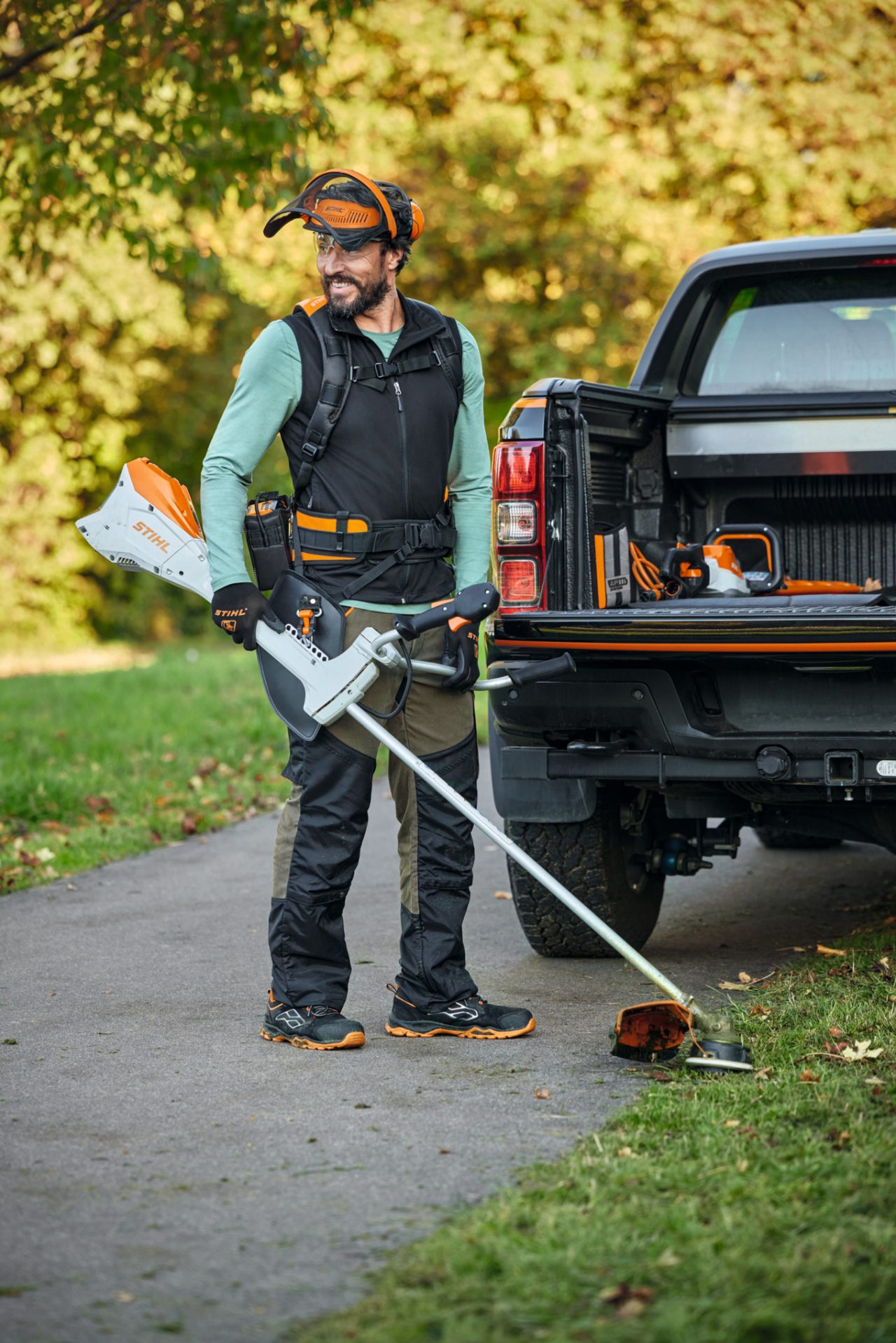 Ein Mann mit dem FS Set und einer Akku-Motorsense STIHL FSA 200 vor einem Auto