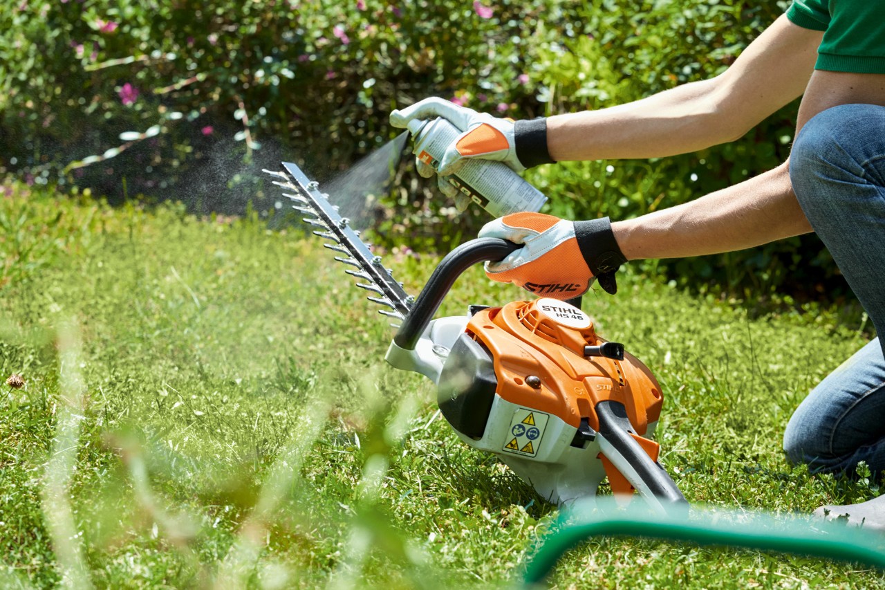  STIHL Benzin-Heckenschere HS 82 T wird auf grünem Rasen eingesprüht, um sie zu reinigen