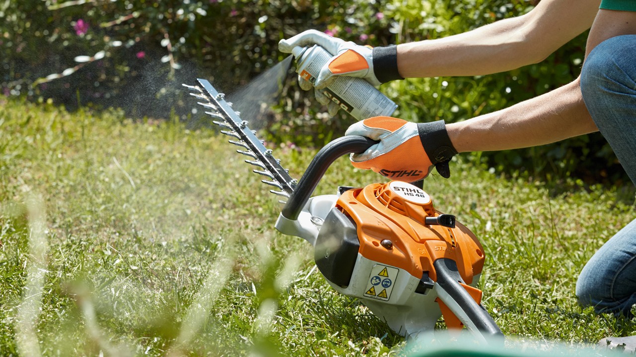 STIHL Benzin-Heckenschere HS 82 T wird auf grünem Rasen eingesprüht, um sie zu reinigen