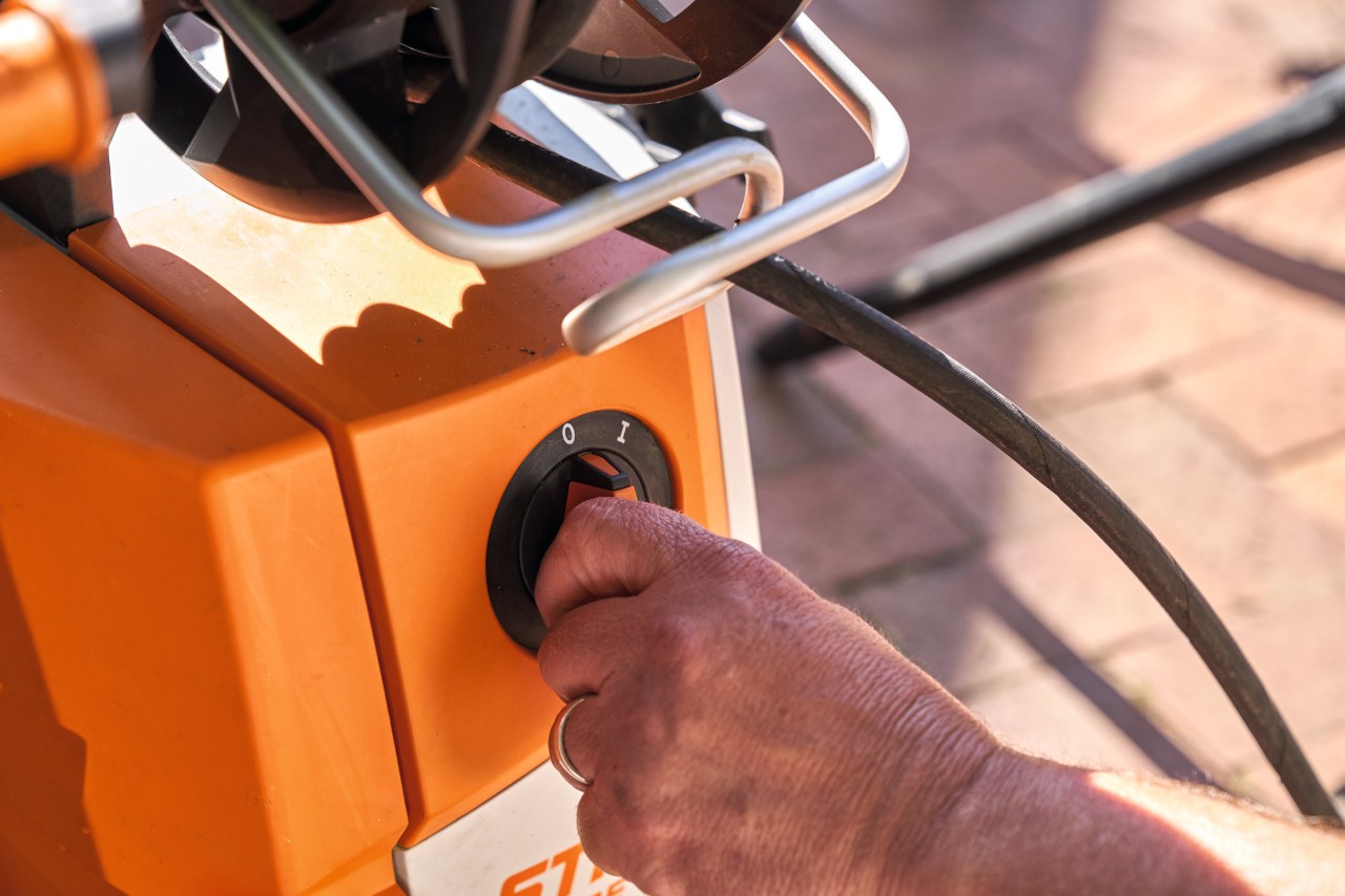 Eine Person dreht den Drehschalter am Hochdruckreiniger STIHL RE 130 PLUS auf 0, um ihn zu benutzen