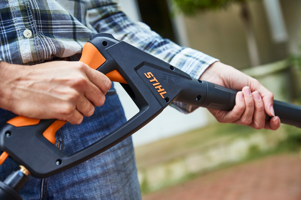 Eine Person betätigt die Spritzpistole des ausgeschalteten Hochdruckreinigers STIHL RE 130 PLUS, um ihn zu benutzen