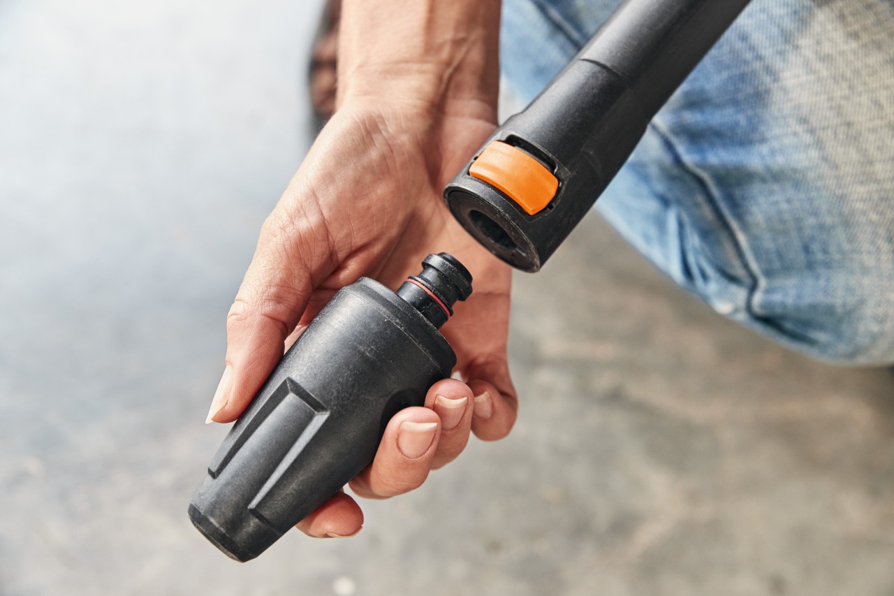 Eine Person montiert einen Aufsatz auf den Hochdruckreiniger STIHL RE 130 PLUS, um ihn zu benutzen