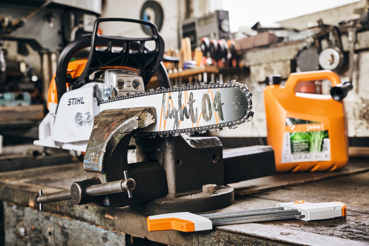 STIHL Benzin-Kettensäge MS 261 C-M mit Führungsschiene Light 04 neben STIHL Kraftstoffgemisch MotoMix vor dem Schärfen