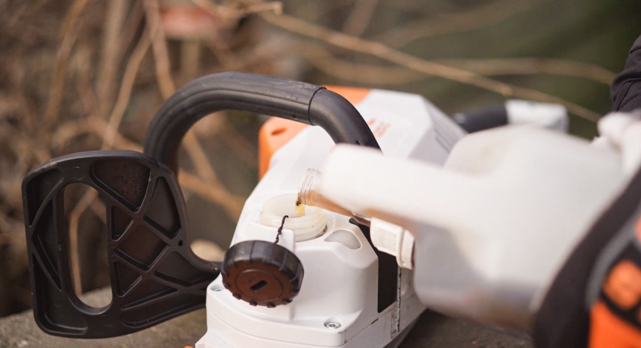 Sägekettenhaftöl wird nach dem Montieren in eine STIHL Akku-Kettensäge MSA 120 eingefüllt