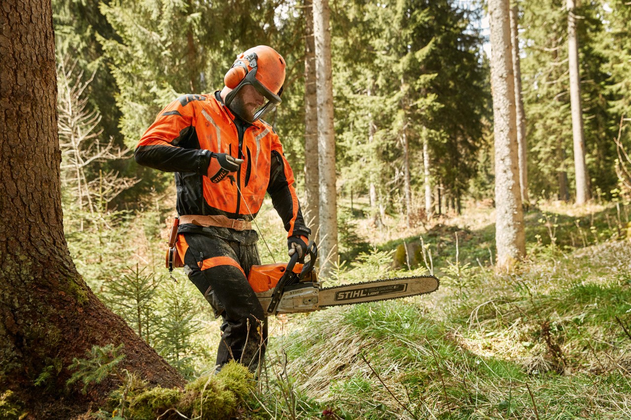 Mann in Schutzausrüstung mit Helmset startet eine STIHL Benzin-Kettensäge MS 462 C-M im Wald