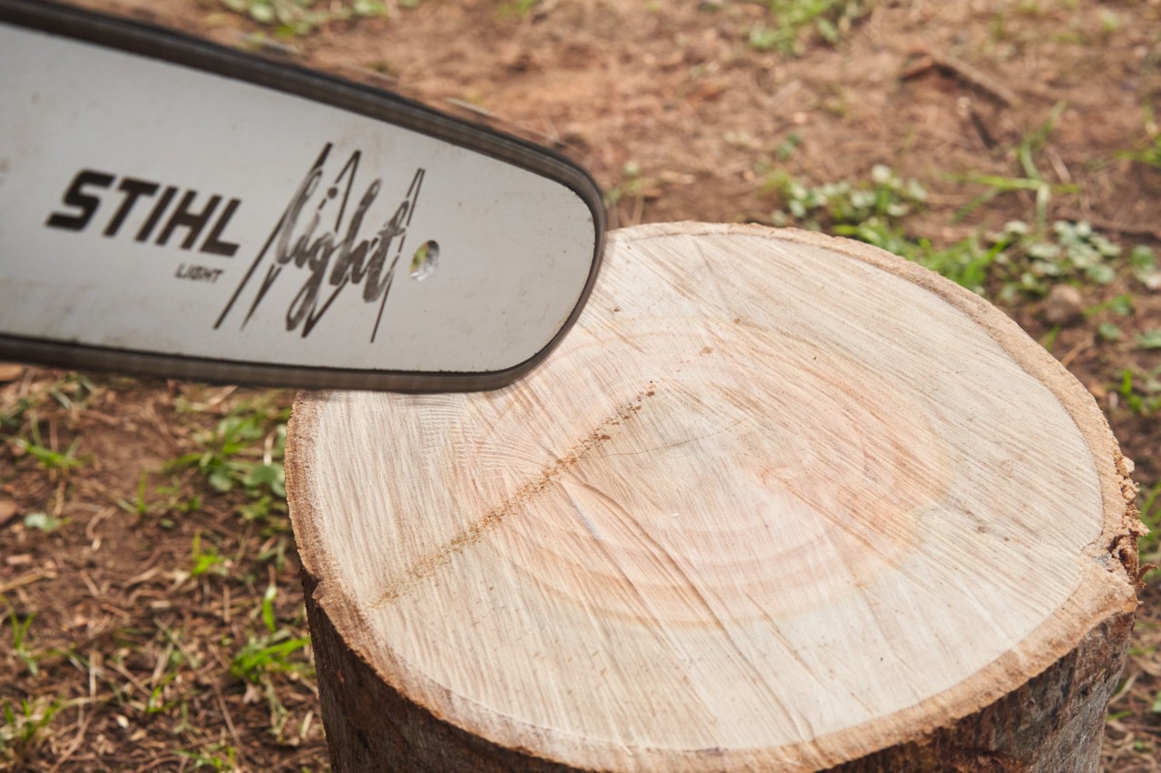 Laufende Motorsäge hinterlässt Ölspur auf hellem Holz