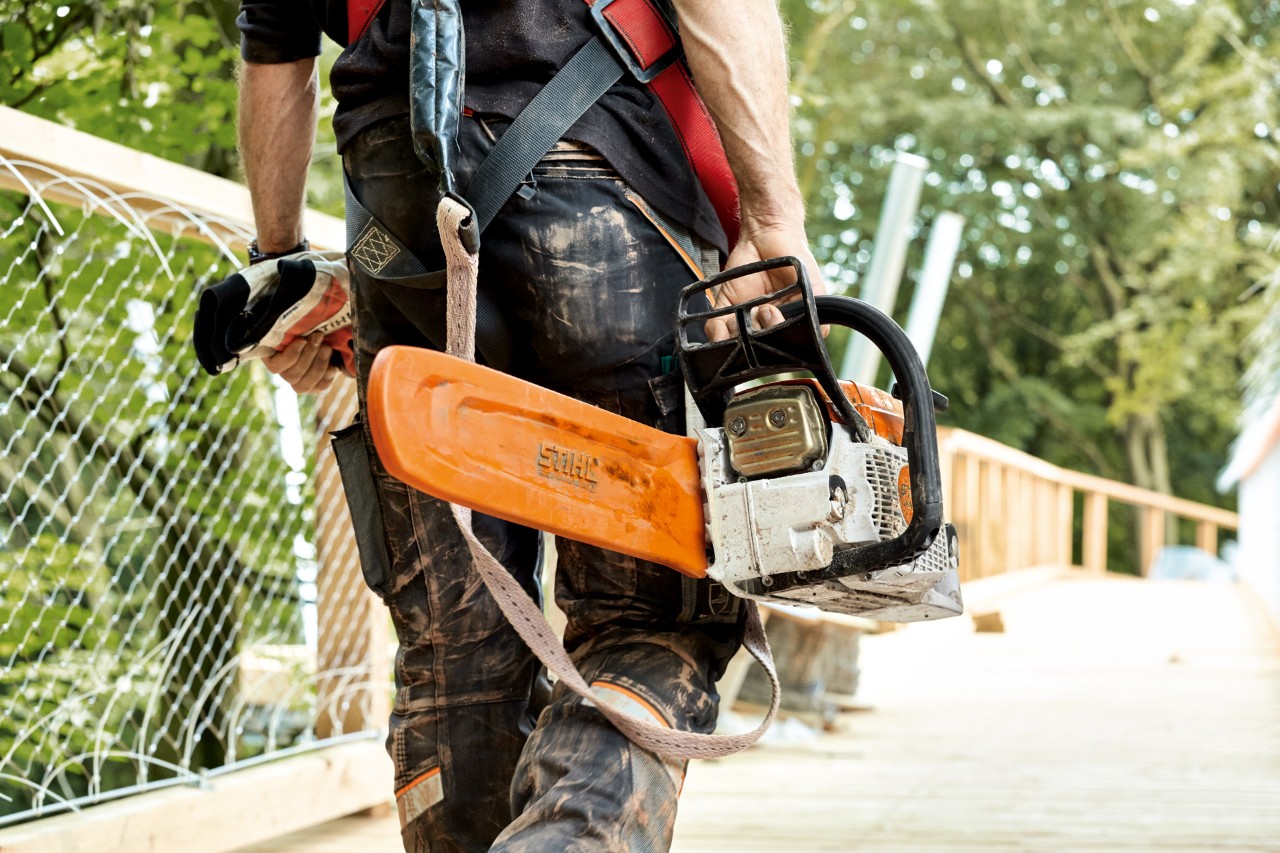 Mann in Schutzkleidung trägt eine STIHL Benzin-Kettensäge MS 261 mit Kettenschutz.