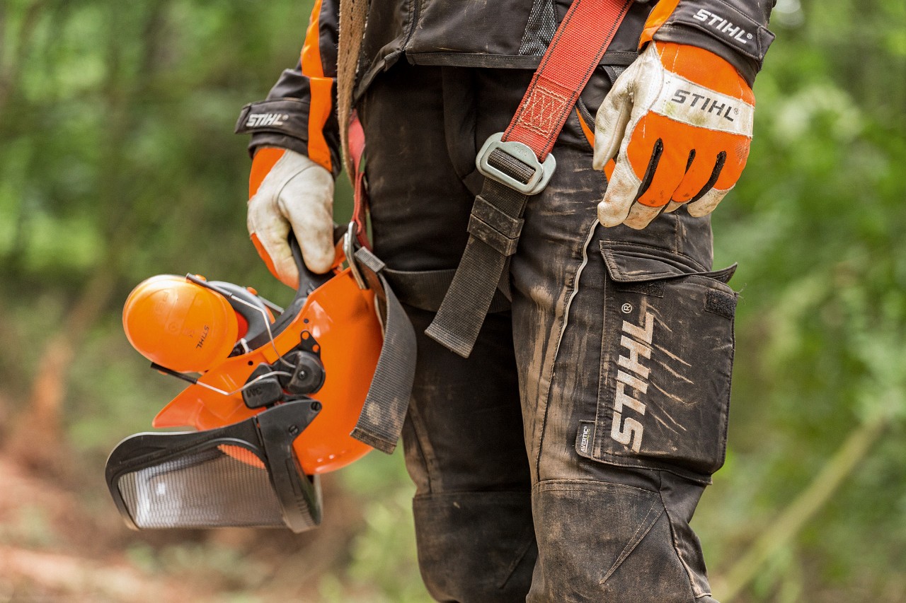 Person mit STIHL Schutzkleidung: Arbeitshandschuhe, Schnittschutzhose und Helmset