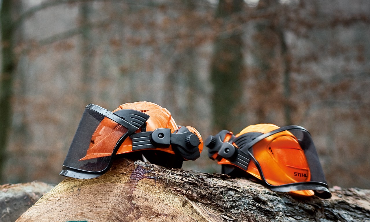 Zwei STIHL Helmsets ADVANCE auf Baumstämmen im Wald