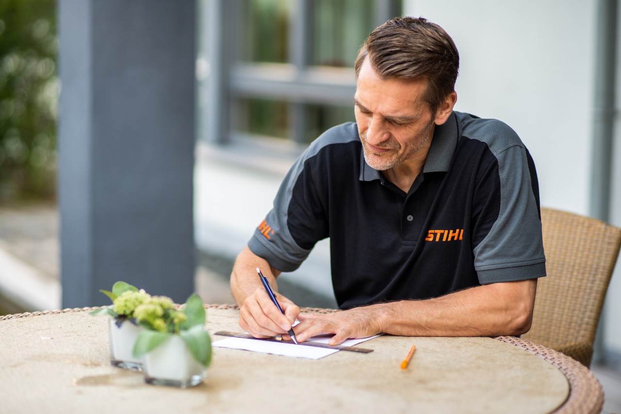 STIHL Fachhändler zeichnet den Grundriss für die Installation des STIHL iMOW® Mähroboters 422