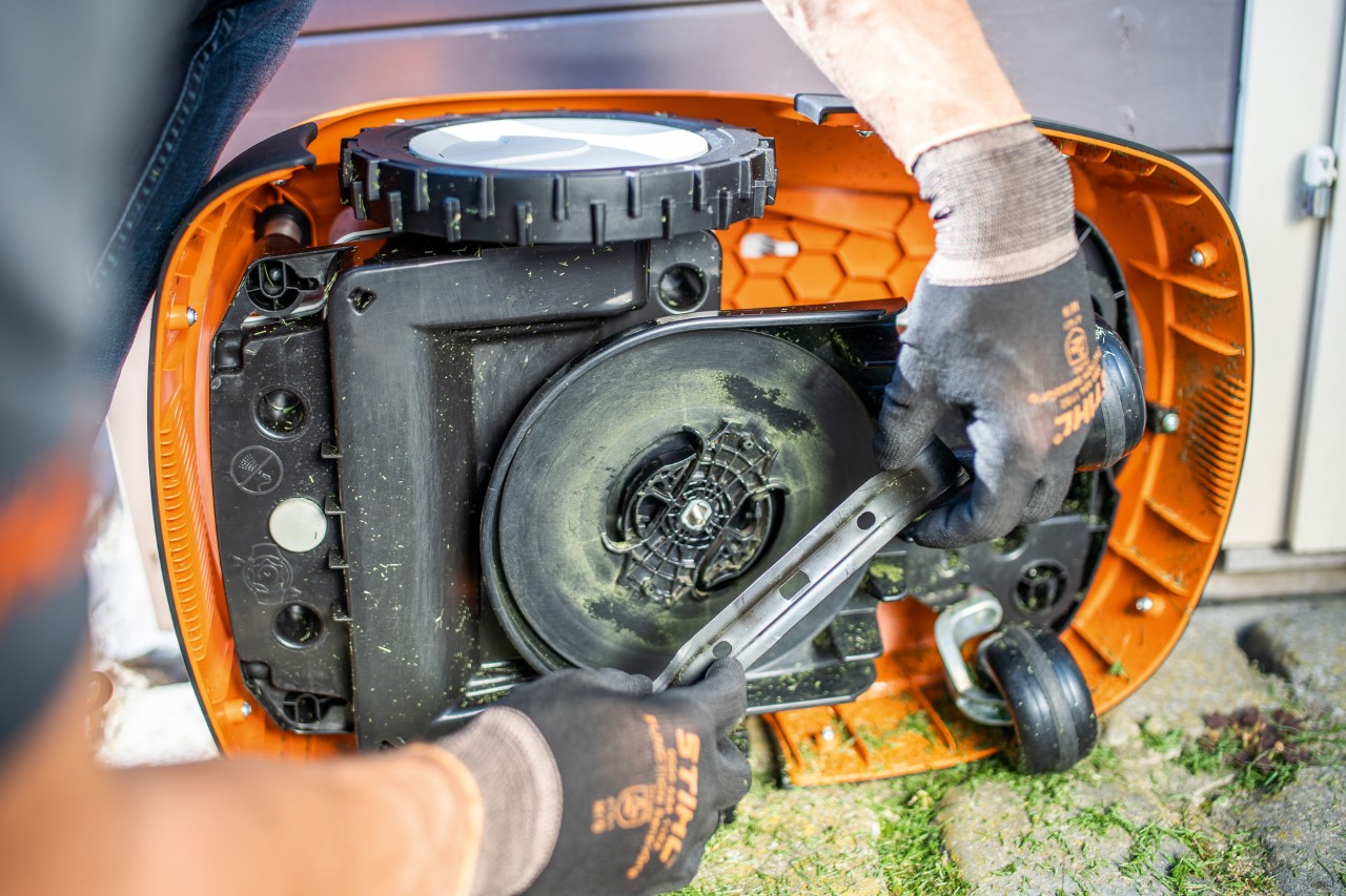 Mähmesser des auf der Seite liegenden STIHL iMOW® Mähroboters werden geprüft