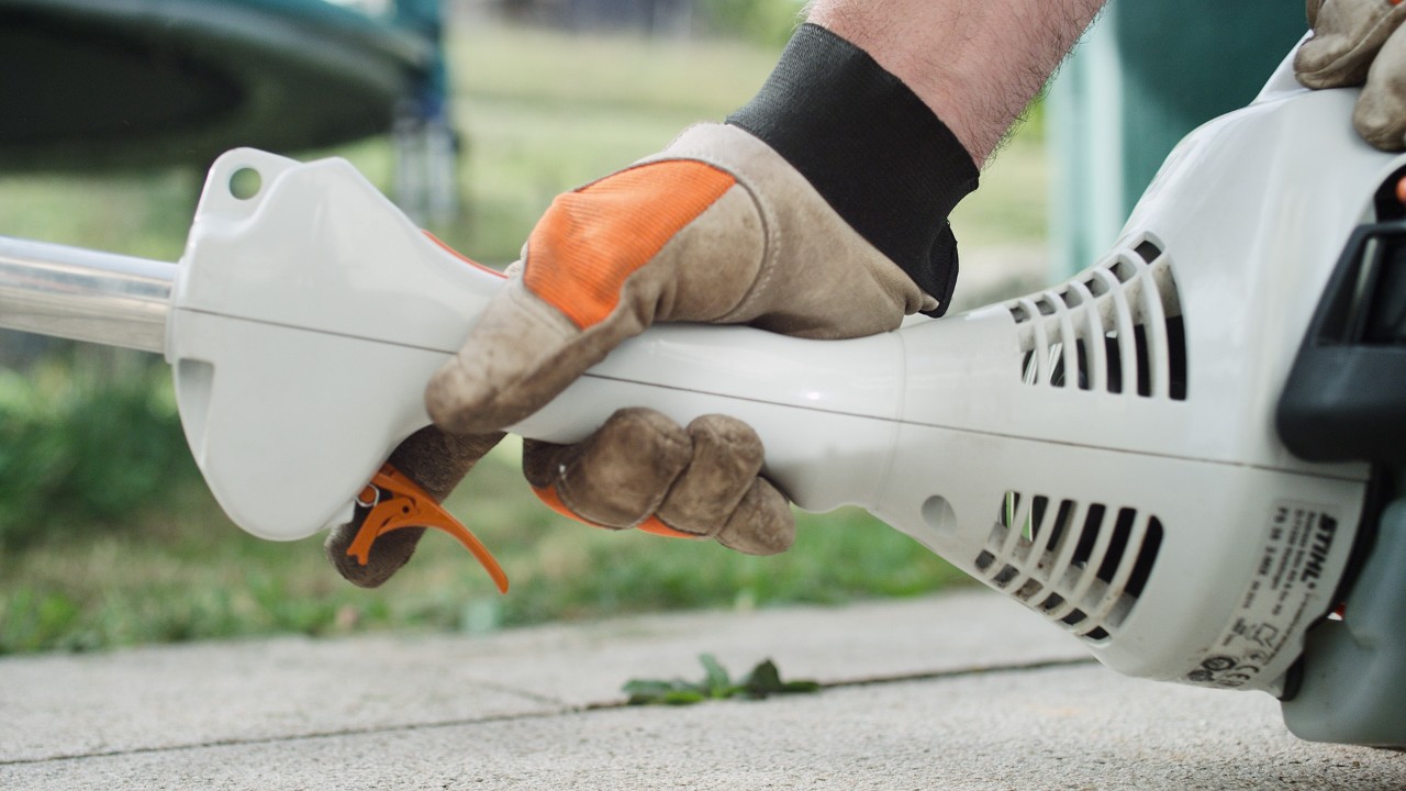 An der Benzin-Motorsense STIHL FS 38 wird der Gashebel gedrückt
