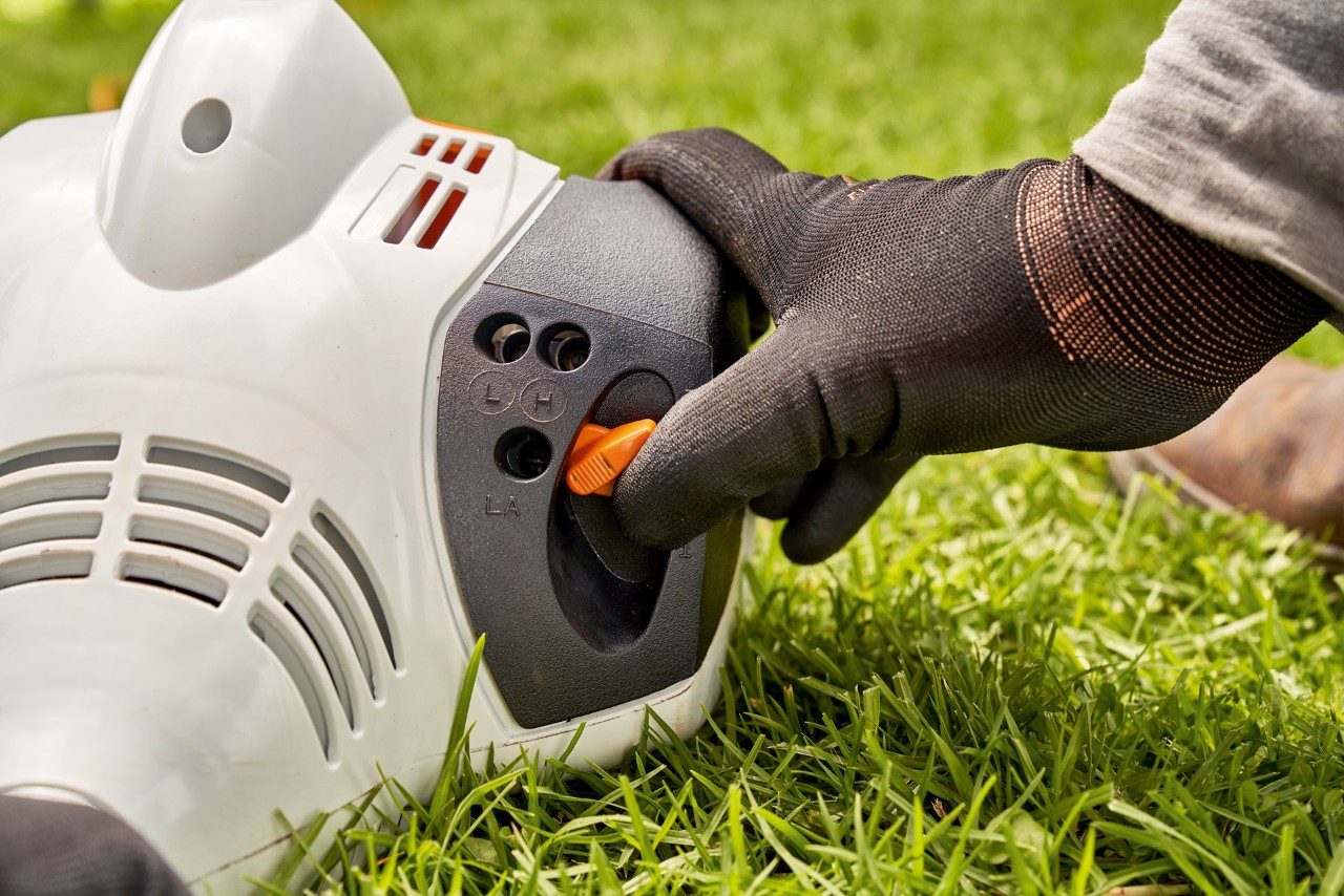 Mann stellt den Hebel der Benzin-Motorsense STIHL FS 56 ein, um sie zu starten