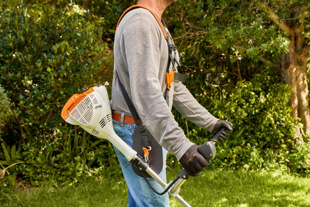 Mann hebt die Benzin-Motorsense STIHL FS 56 vom Boden hoch
