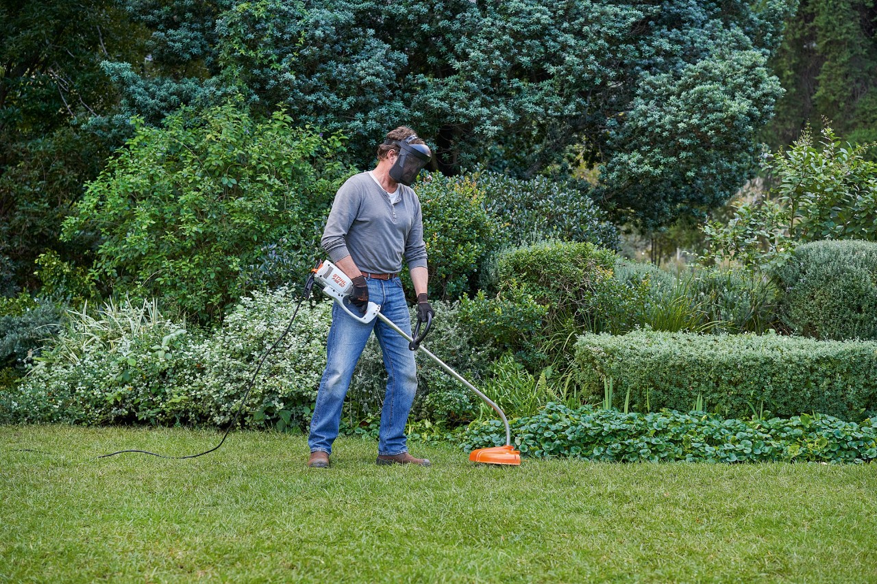 Mann mit Elektro-Motorsense STIHL FSE 60 nimmt einen sicheren Stand ein