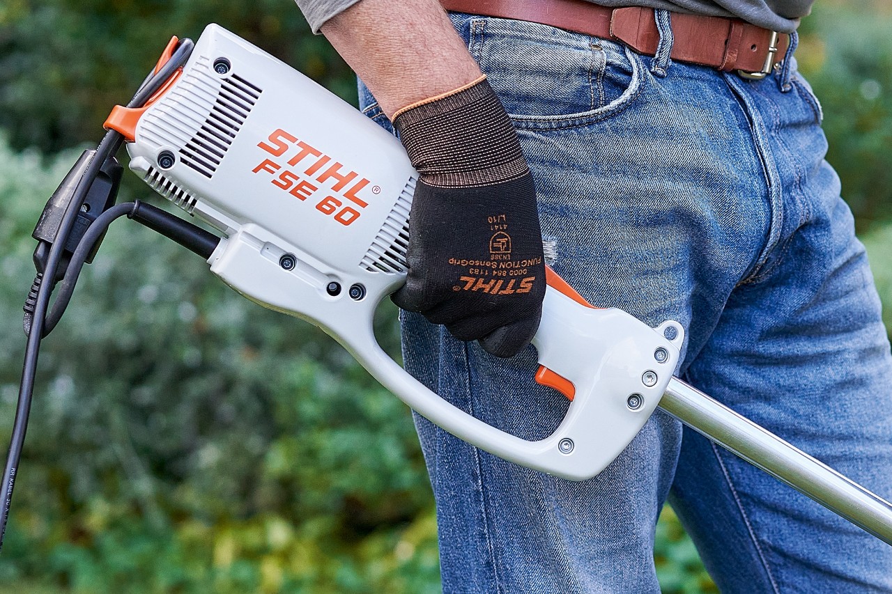 Mann betätigt Schalter, um die Elektro-Motorsense STIHL FSE 60 auszuschalten.