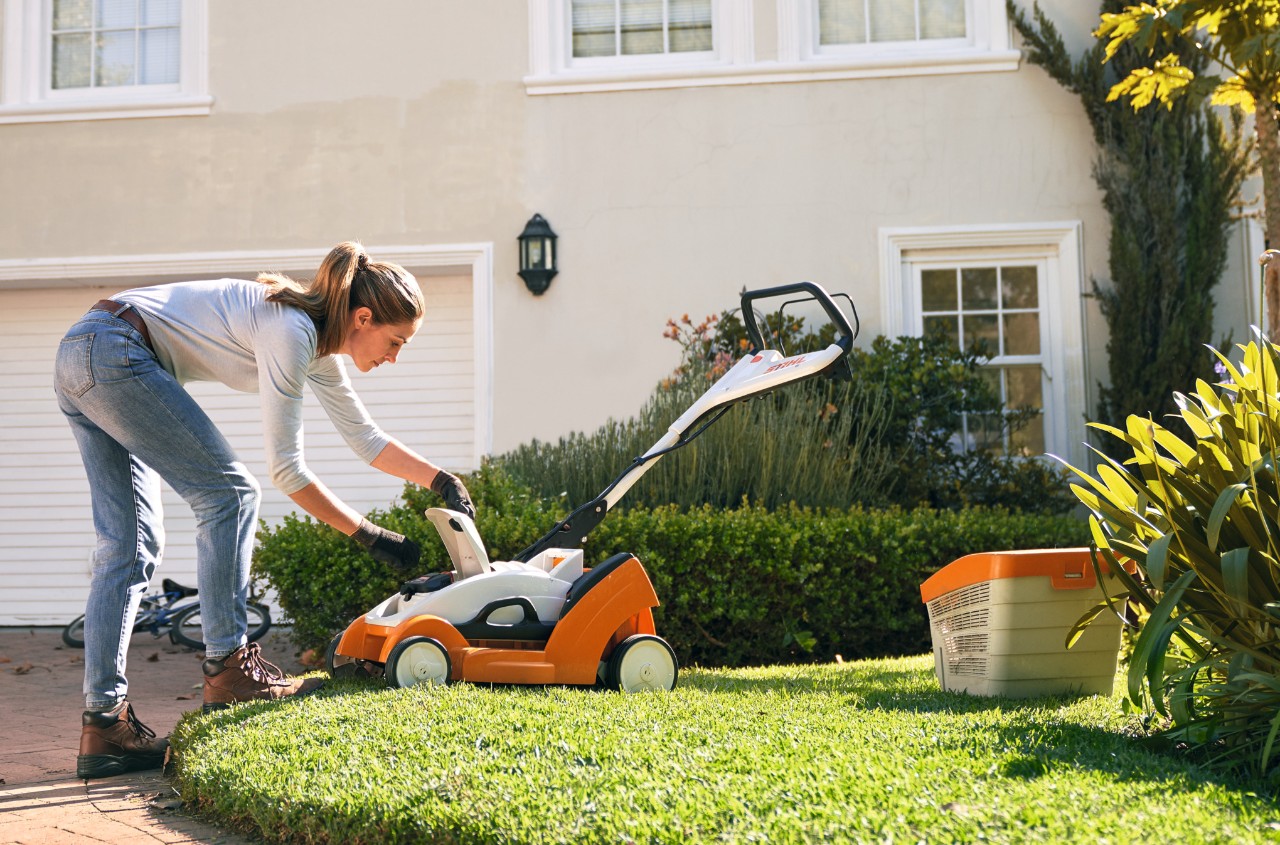 Deckel eines STIHL Akku-Rasenmähers RMA 339 C vor einem weißen Haus