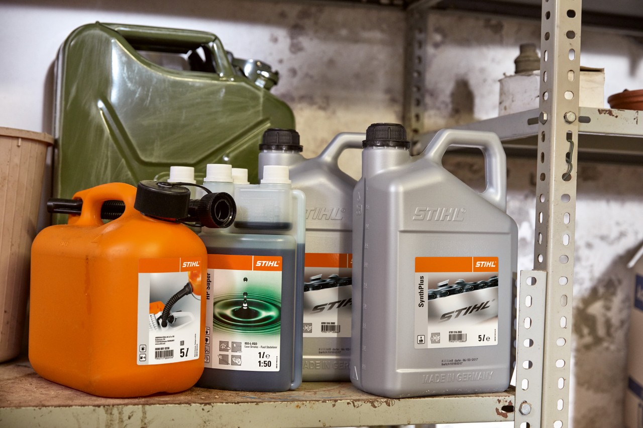 Behälter mit STIHL Betriebsstoffen in einer Garage, um den Rasenmäher zu tanken