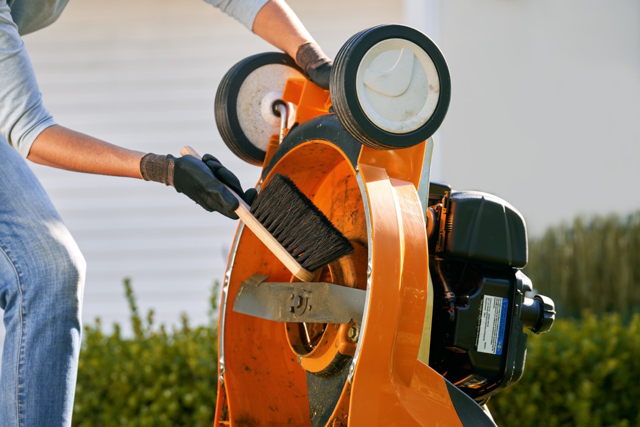 Unterseite vom STIHL Benzin-Rasenmäher RM 448 TC wird mit einer Bürste gesäubert