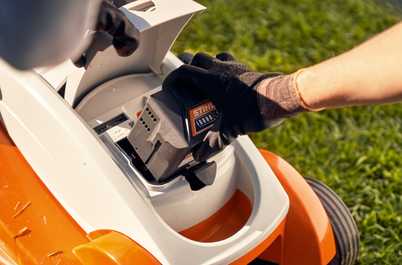 Person entfernt Akku aus einem STIHL Akku-Rasenmäher RMA 339C, um ihn winterfest zu machen