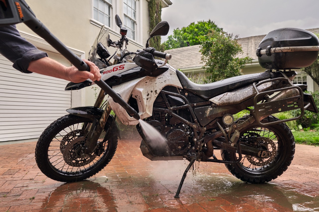 Motorrad wird einem weißen Haus mit einem STIHL Hochdruckreiniger RE 130 plus gereinigt