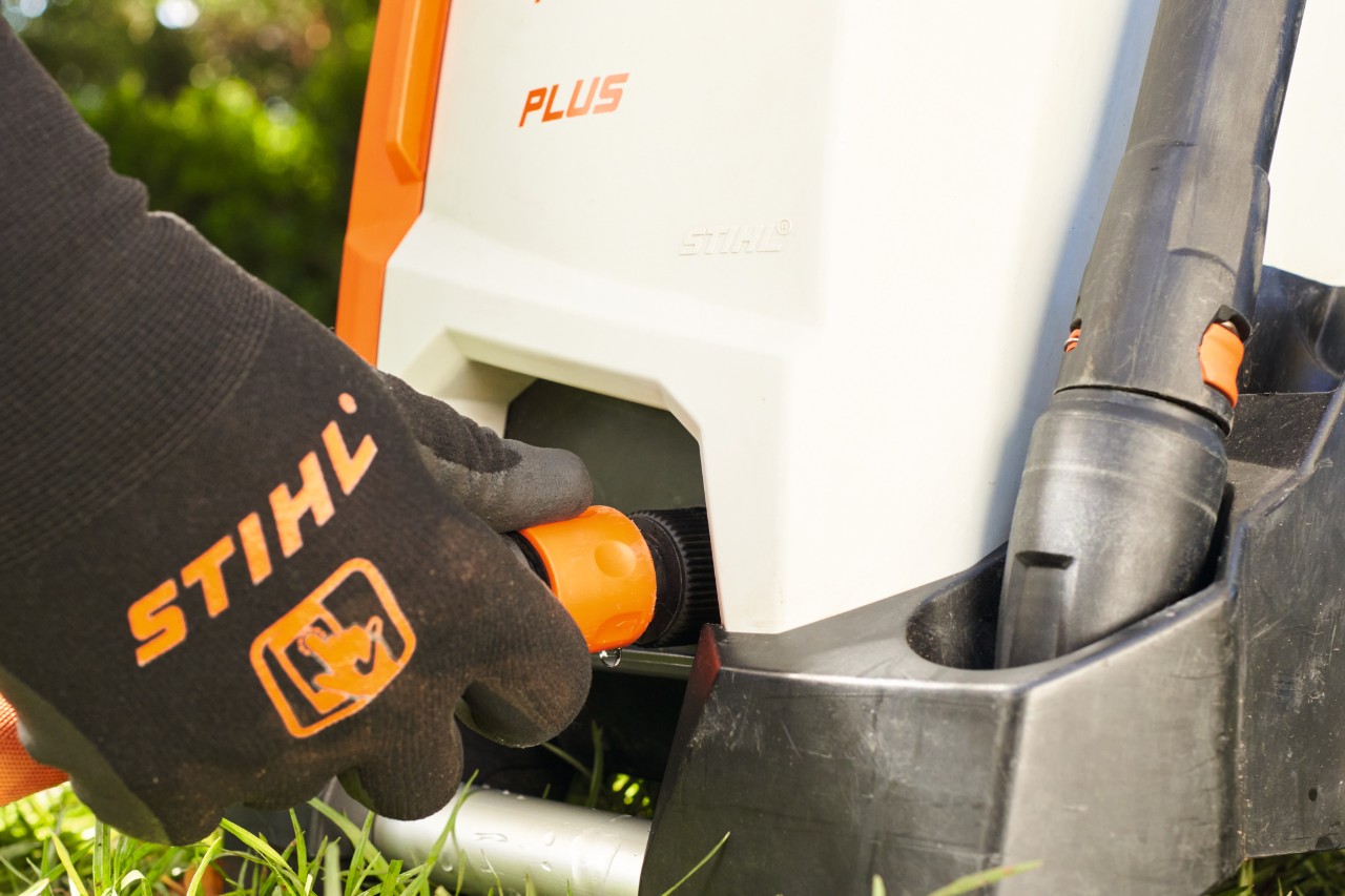 Nahaufnahme, wie ein Gartenschlauch an einen STIHL Hochdruckreiniger angesteckt wird