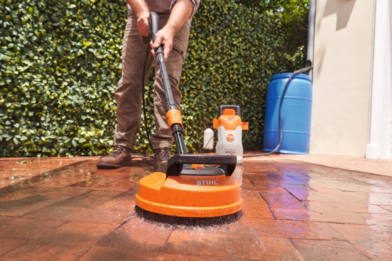 Nahaufnahme, wie mit dem Elektro-Hochdruckreiniger STIHL RE 80 X die Pflastersteine auf einer Terrasse gereinigt werden