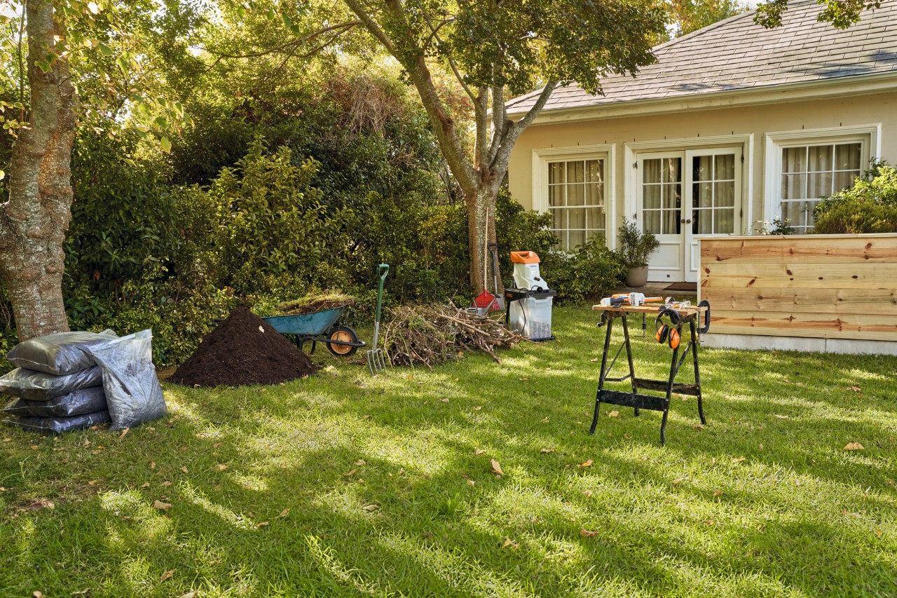 Werkzeug, Material und STIHL Geräte zum Bauen und Befüllen eines Hochbeetes, darunter der Elektro-Gartenhäcksler STIHL GHE 140 L sowie der Gehölzschneider STIHL GTA 26