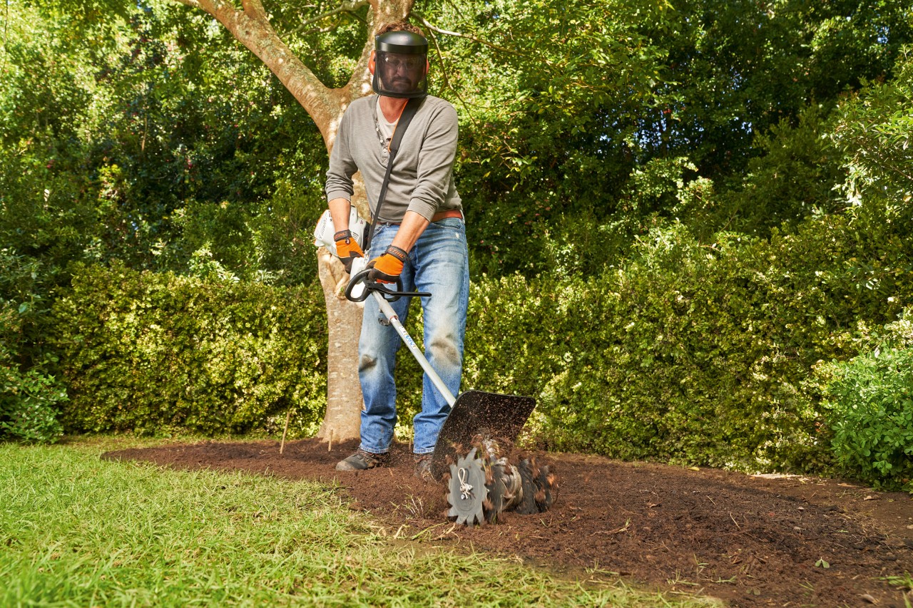 Mit einem STIHL Kombisystem KM 56 RC-E arbeitet ein Mann Humus in den Boden ein