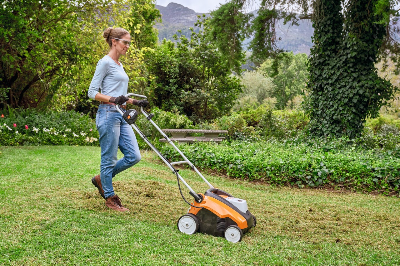 Eine Frau vertikutiert mit einem Akku-Rasenlüfter STIHL RLA 240 den Rasen