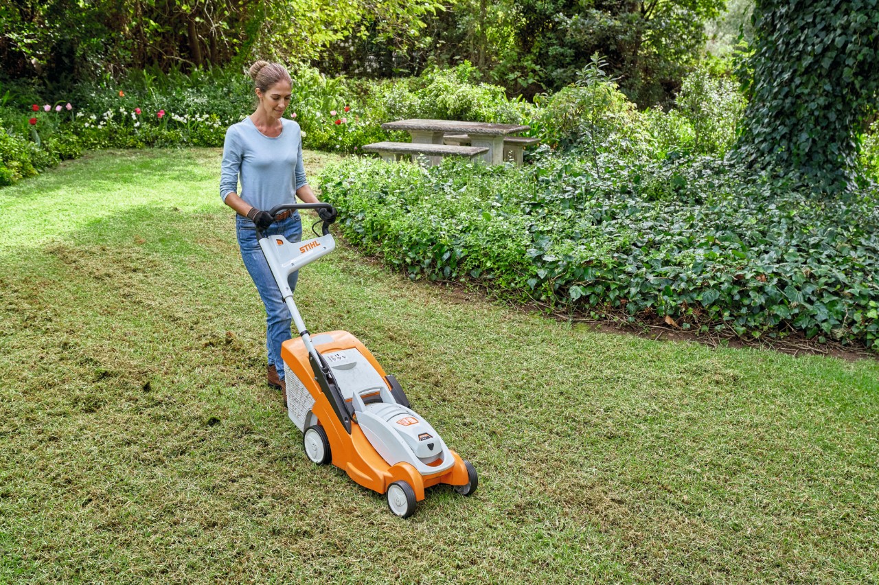 Eine Frau mäht eine Frühlingswiese mit einem Akku-Rasenmäher STIHL RMA 339 C