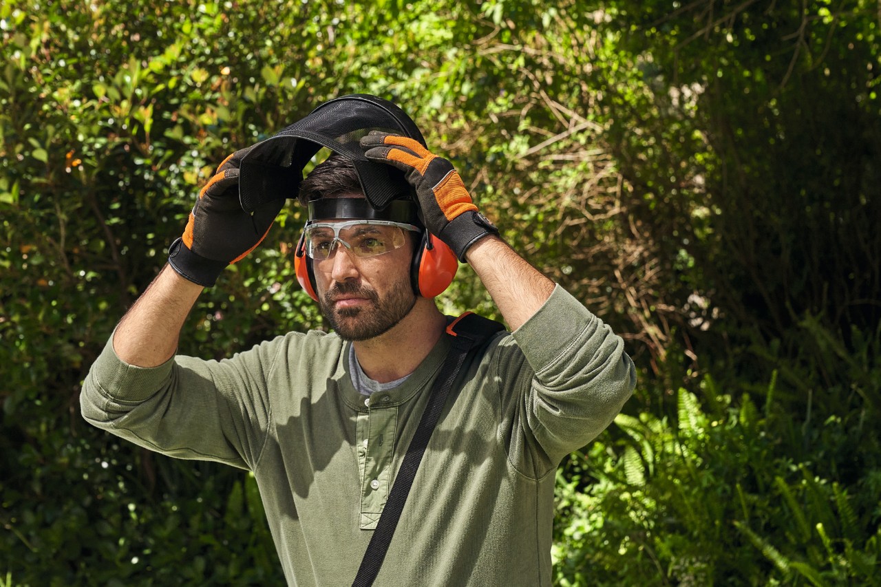 Ein Mann in STIHL Arbeitsschutzausrüstung auf einem Gartengrundstück 