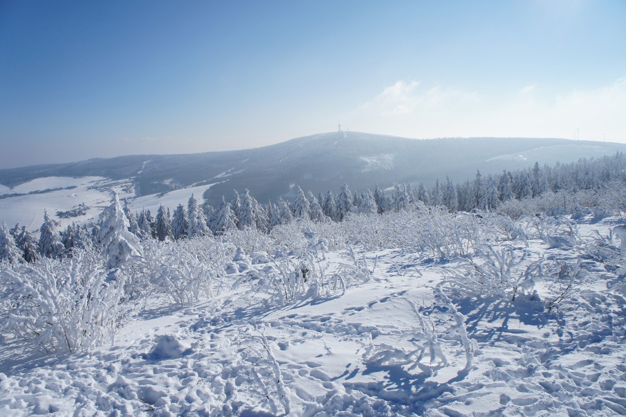 Verschneite Landschaft aus der Vogelperspektive an einem sonnigen Tag, hügeliges Panorama im Hintergrund