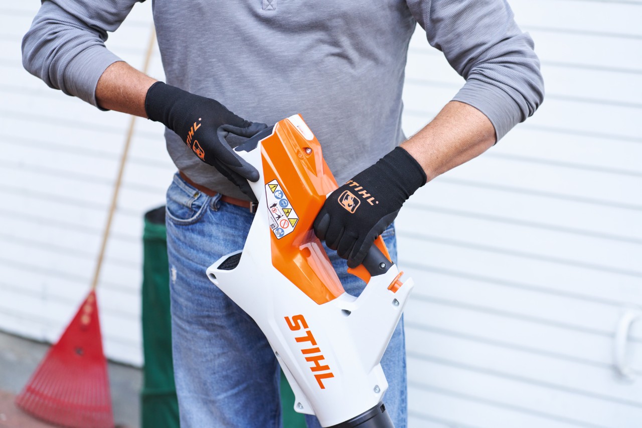 Person mit grauem Pullover, Jeans und STIHL Blasgerät in der Hand