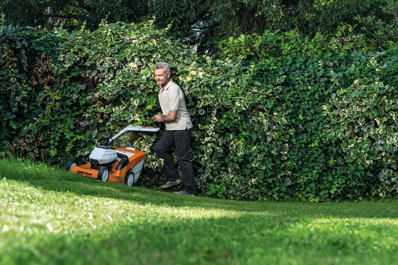 Ein Mann mäht mit einem Akku-Rasenmäher STIHL RMA 448 TC einen Hang  