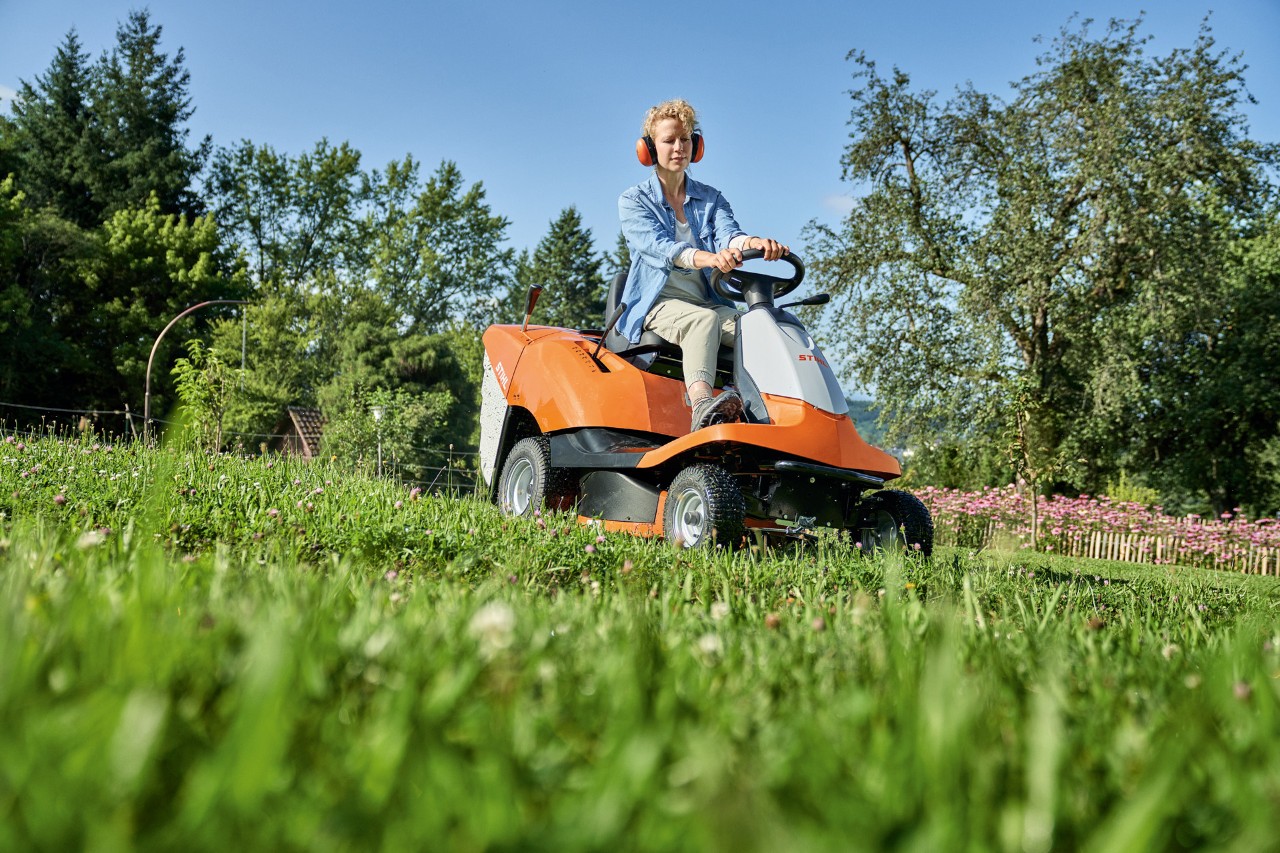 Eine Frau mäht mit einem Aufsitzmäher STIHL RT 4082 einen Hang 