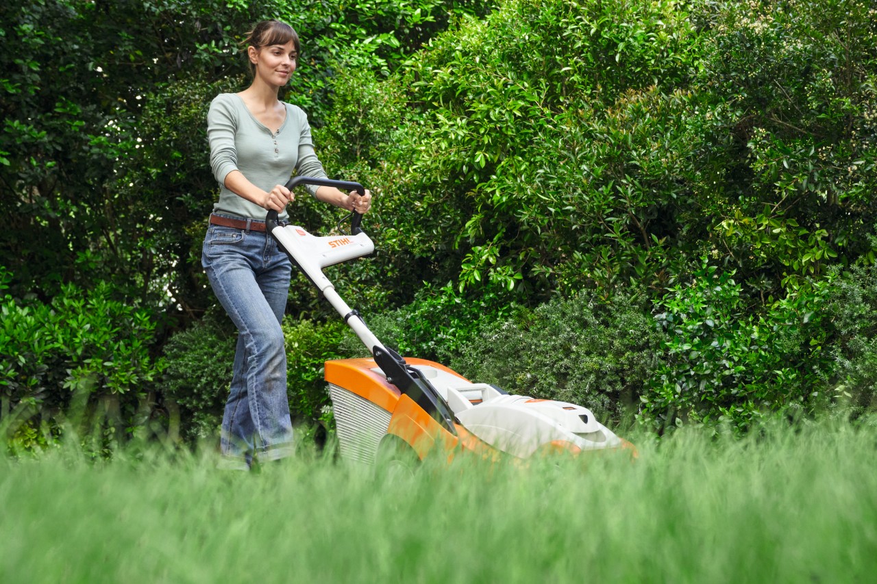 Eine Frau mäht den Rasen mit einem STIHL Rasenmäher