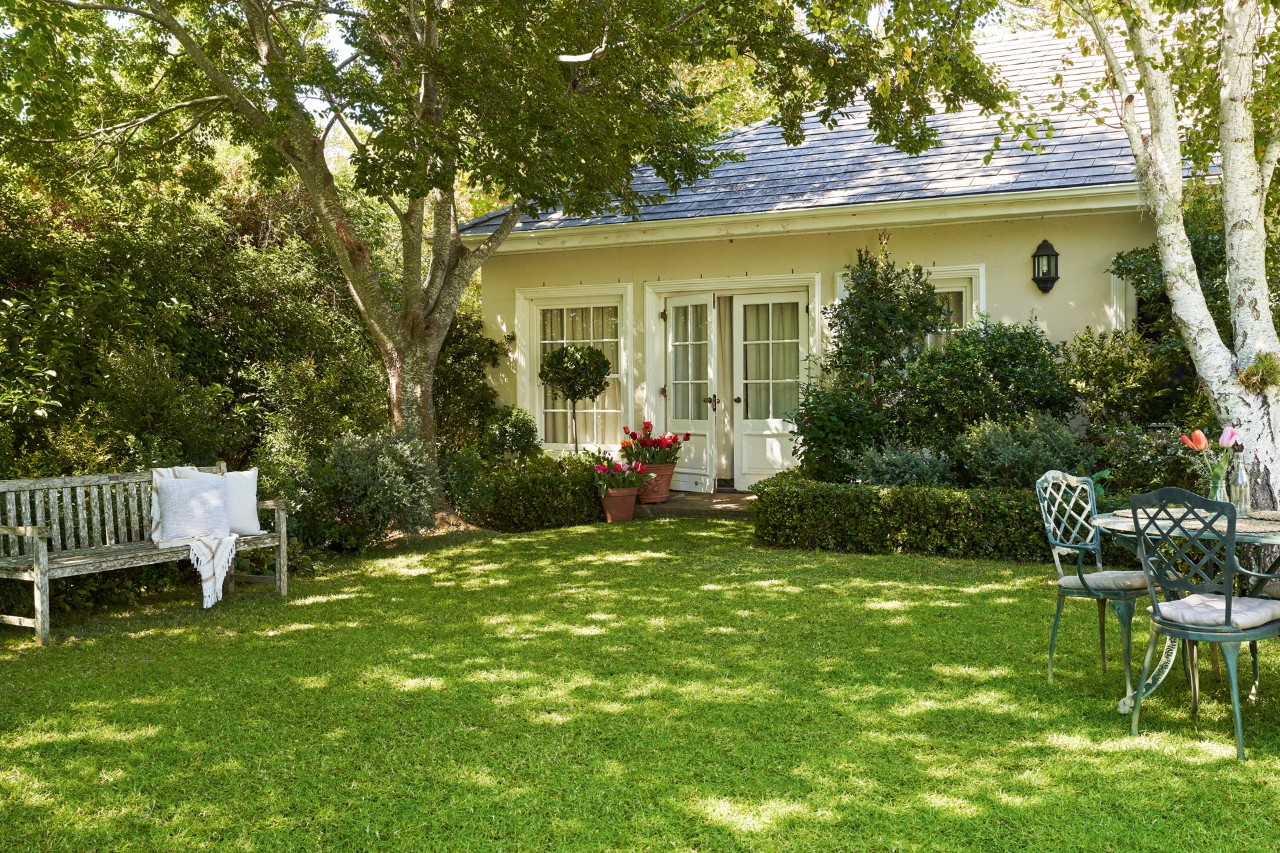 Garten mit grünem, gesundem Rasen nach dem Rasenkalken mit Haus im Hintergrund