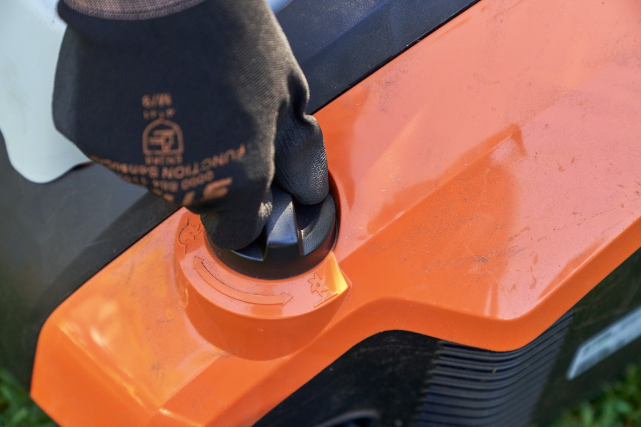 Nahaufnahme: Hand mit STIHL Arbeitshandschuh FUNCTION SENSOTOUCH dreht am Drehgriff des STIHL Akku-Rasenlüfters RLA 240.