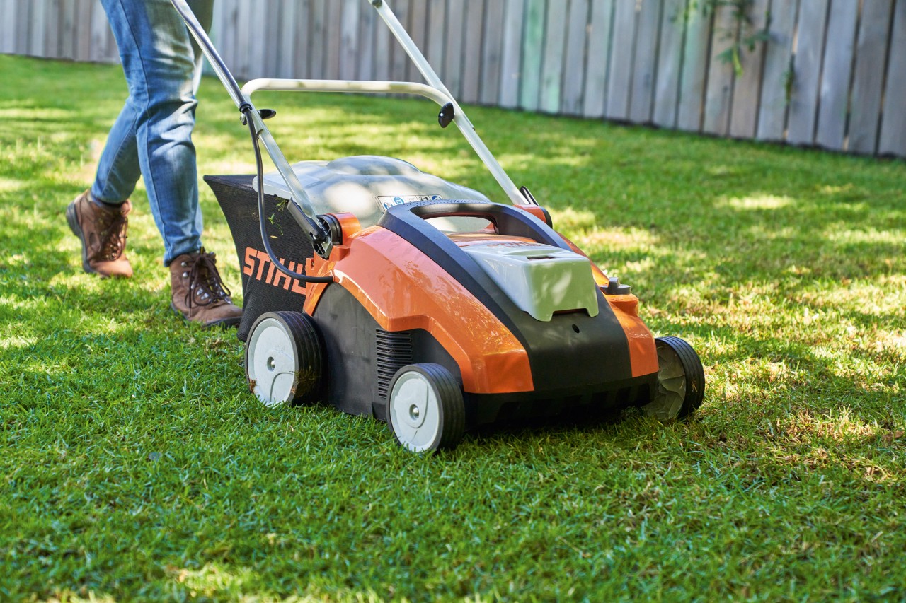 STIHL Akku-Rasenlüfter RLA 240 beim Rasenlüften einer grünen Rasenfläche